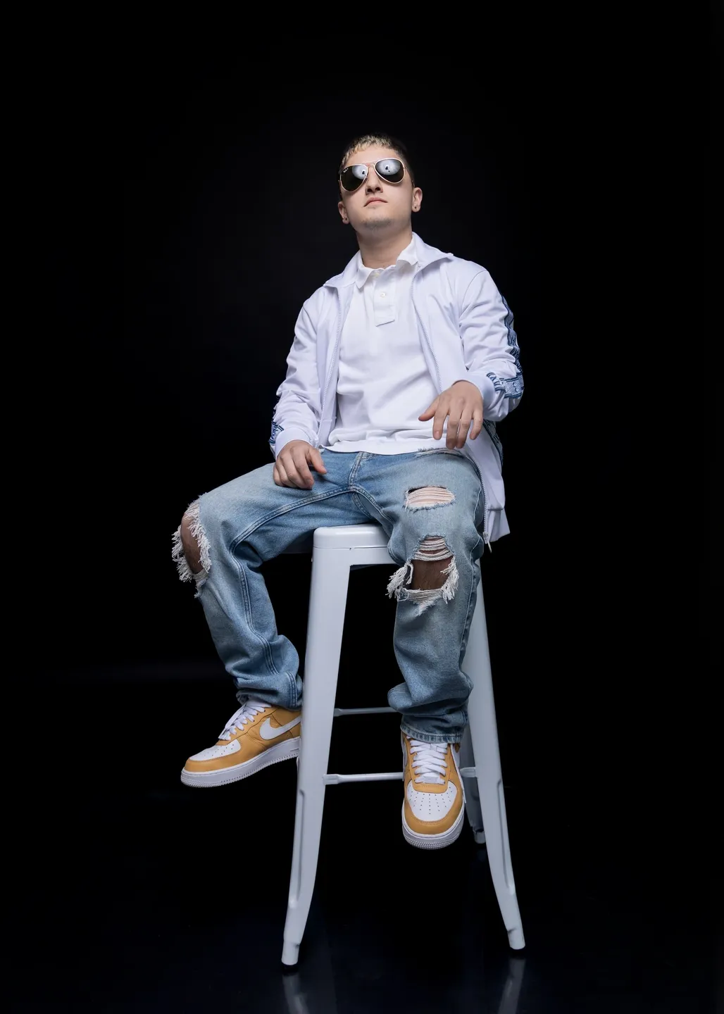 A man sitting on top of a white stool.