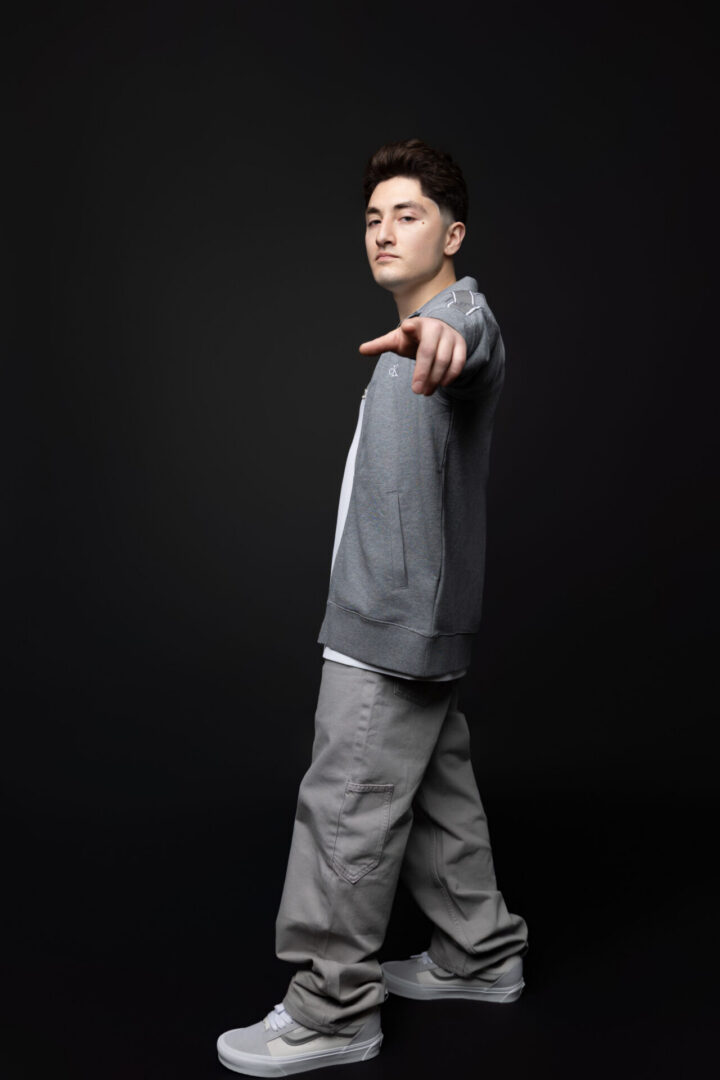Young man pointing at camera in gray clothes