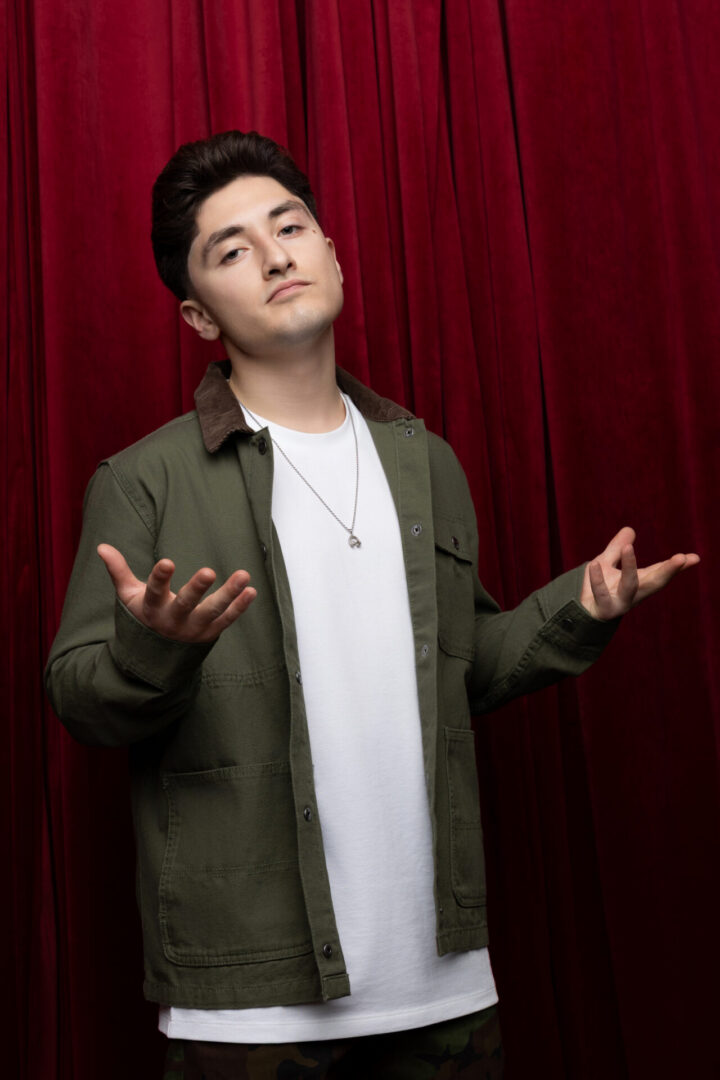 Young man posing with open arms, red curtain